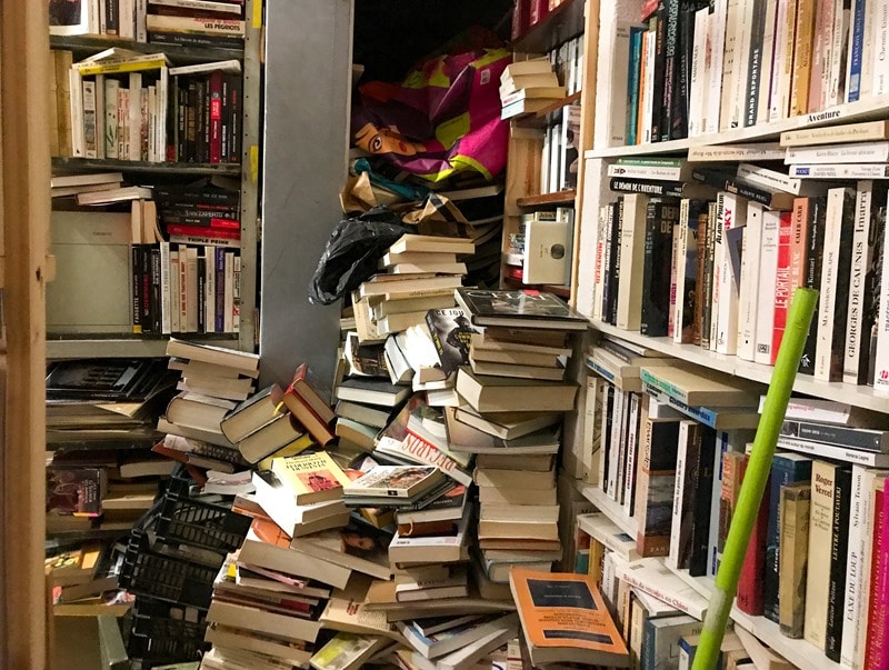 La boutique du bouquiniste et ses piles de livres écroulées dans tous les coins