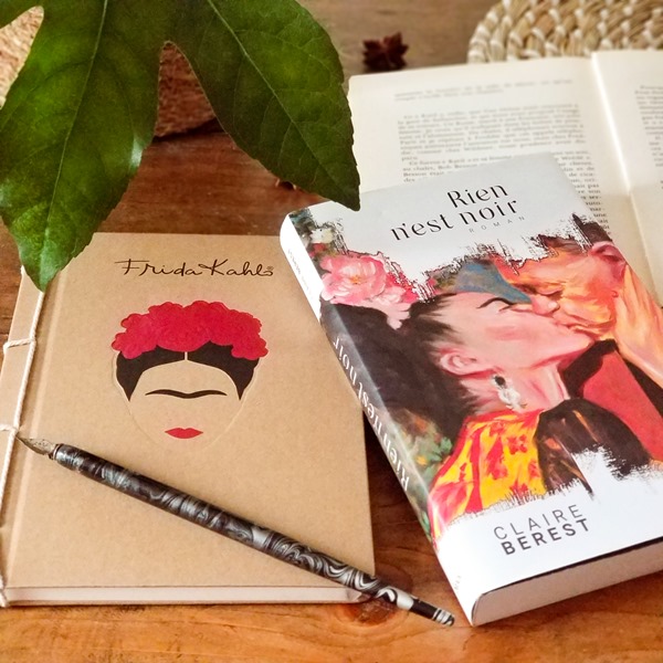 Claire Berest - Rien n’est noir Roman "Rien n'est noir" de Claire Berest posé sur une table avec un livre ouvert et un carnet sur lequel figure le visage de Frida Kahlo et un stylo plume