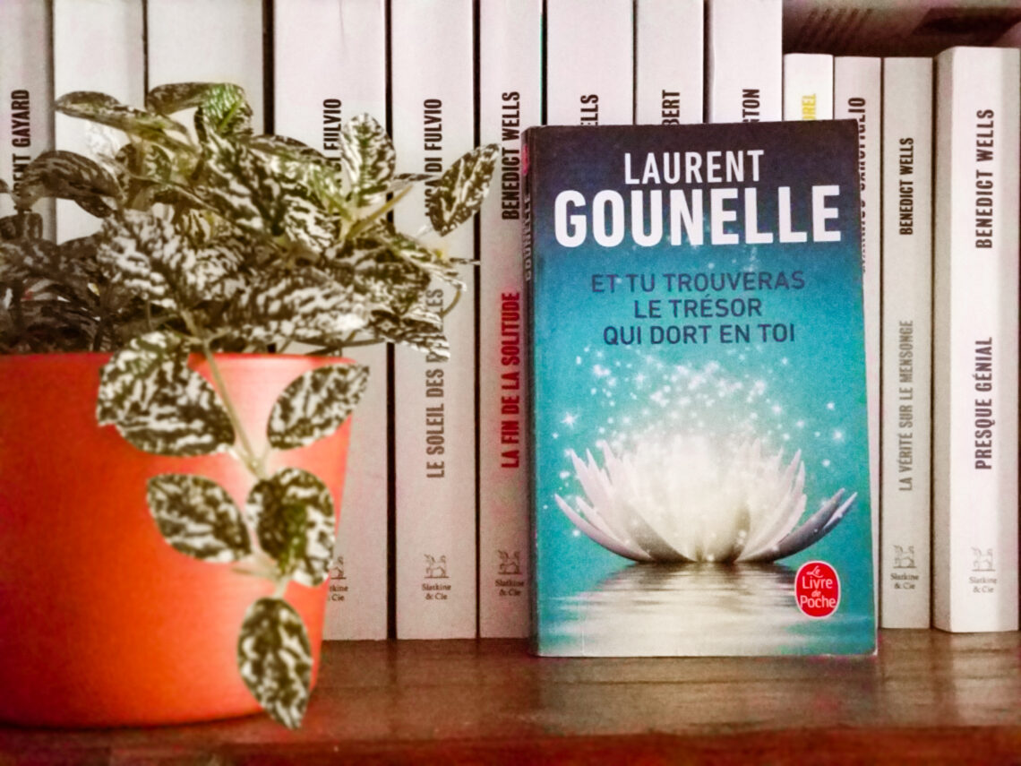 Livre posé dans une bibliothèque - il s'agit de "et tu trouveras le trésor qui dort en toi" de Laurent Gounelle