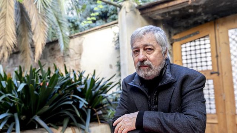 Sorj Chalandon Sorj Chalandon pose en extérieur devant une porte en bois et dans un jardin