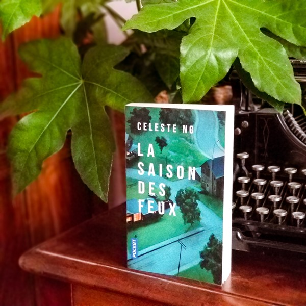 La saison des feux de Celeste Ng Livre "La saison des feux" de Celeste Ng posé sur un meuble devant une machine à écrire et une plante verte