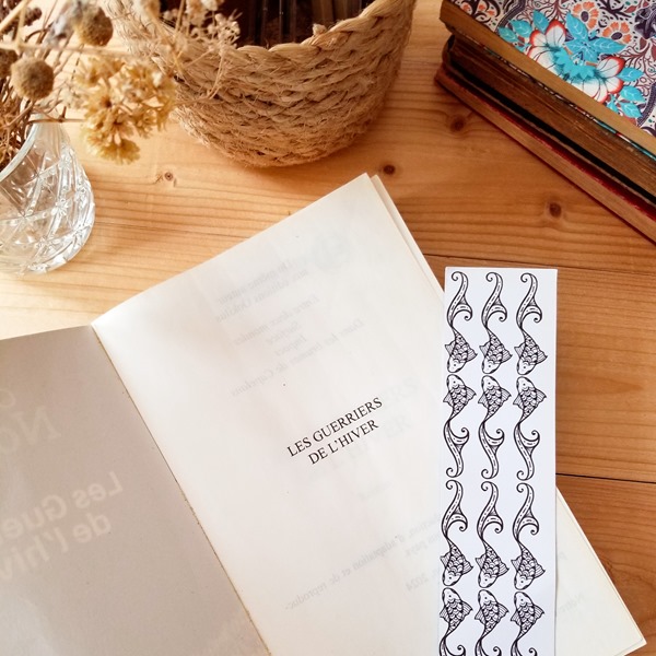 les guerriers de l’hiver - Olivier Norek Livre "les guerriers de l’hiver" de Olivier Norek posé ouvert sur la page du titre, sur une table avec un marque page.